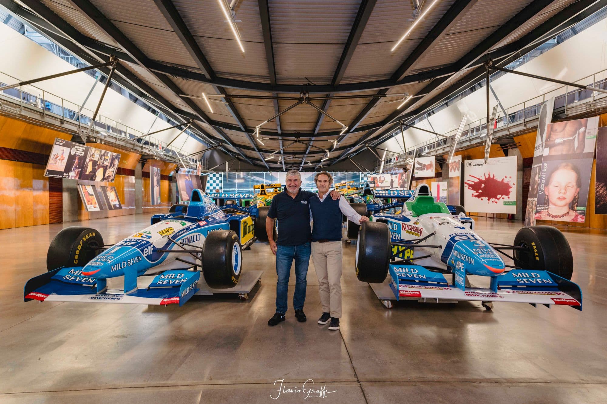 Two members of the GAM team in front of Formula 1 cars in a museum
