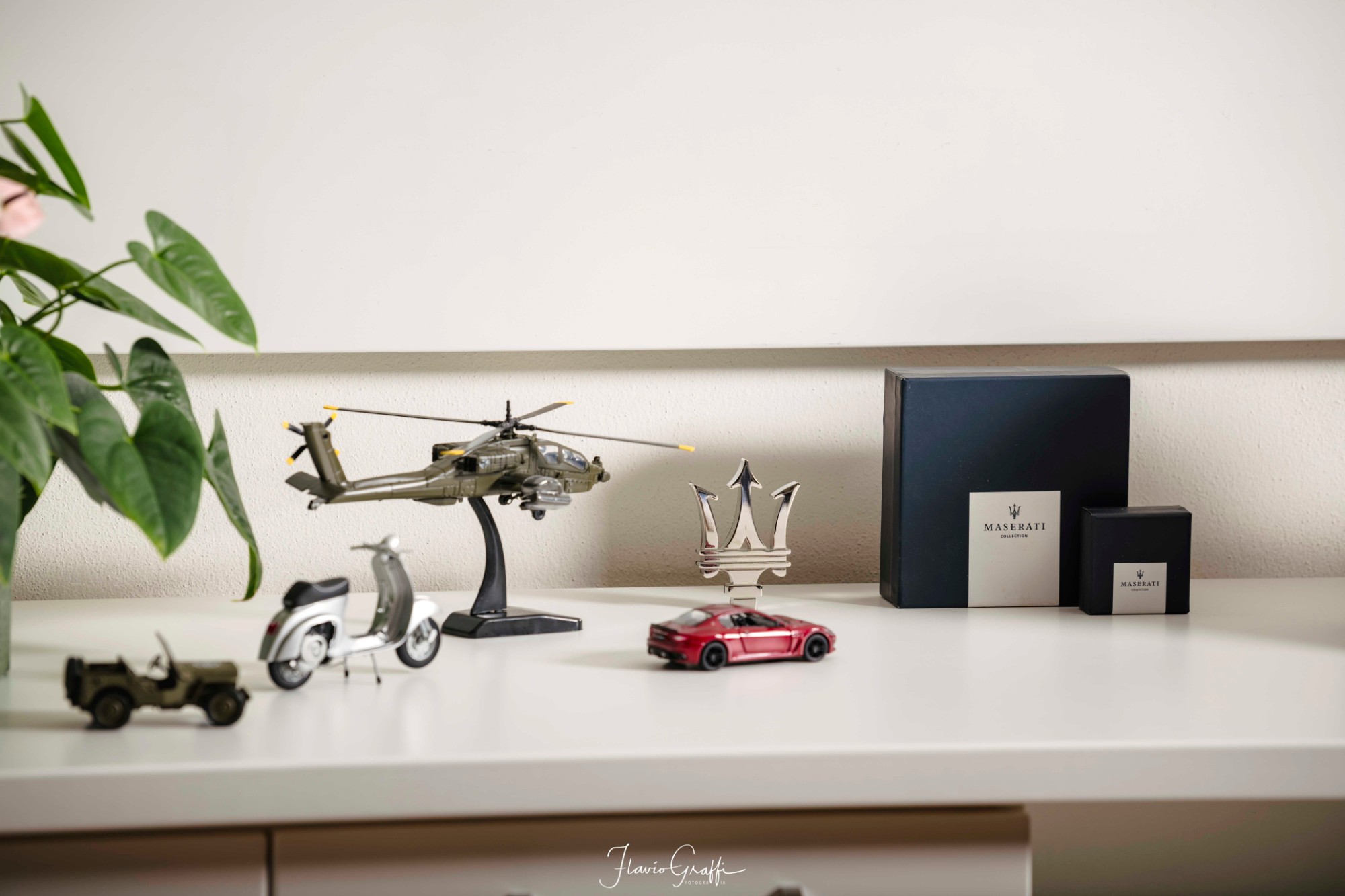 Model helicopter, Vespa, jeep and Maserati on a shelf